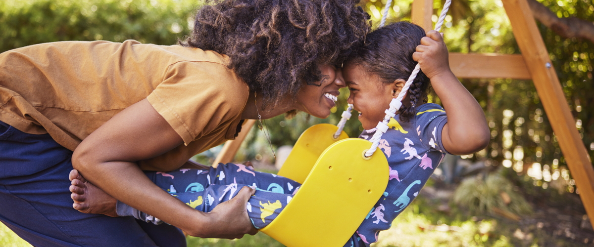 Mother pushing daughter on swing